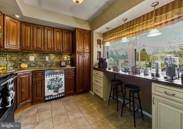 a kitchen with stainless steel appliances granite countertop a stove a sink dishwasher and a refrigerator with wooden cabinets