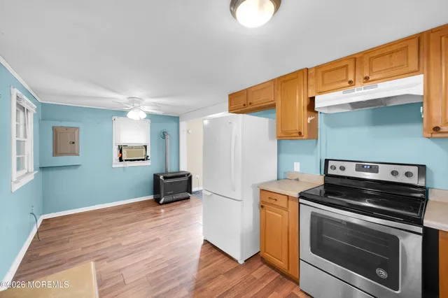 a kitchen with stainless steel appliances granite countertop a refrigerator a sink dishwasher a stove with wooden cabinets and wooden floor