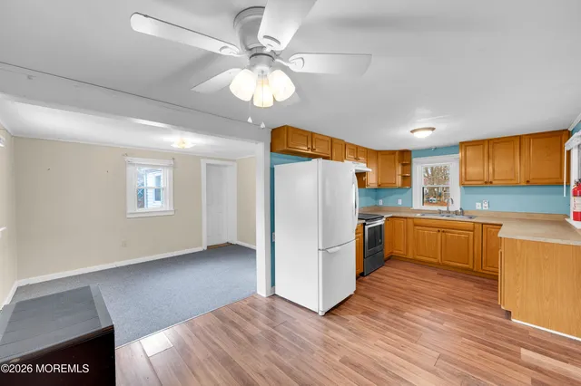 a view of a kitchen with a refrigerator a ceiling fan and wooden floor