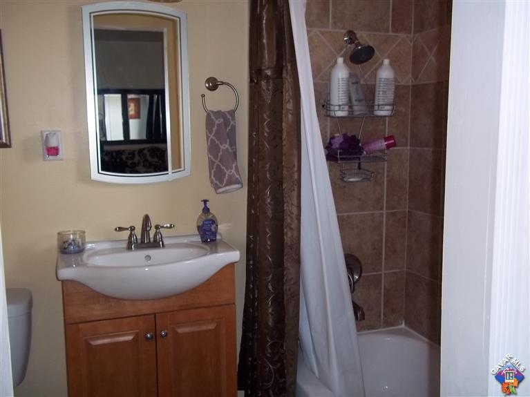 43940 3rd Street East Lancaster, CA 93535 - Photo 13 of 18 a bathroom with a sink a mirror a vanity and shower