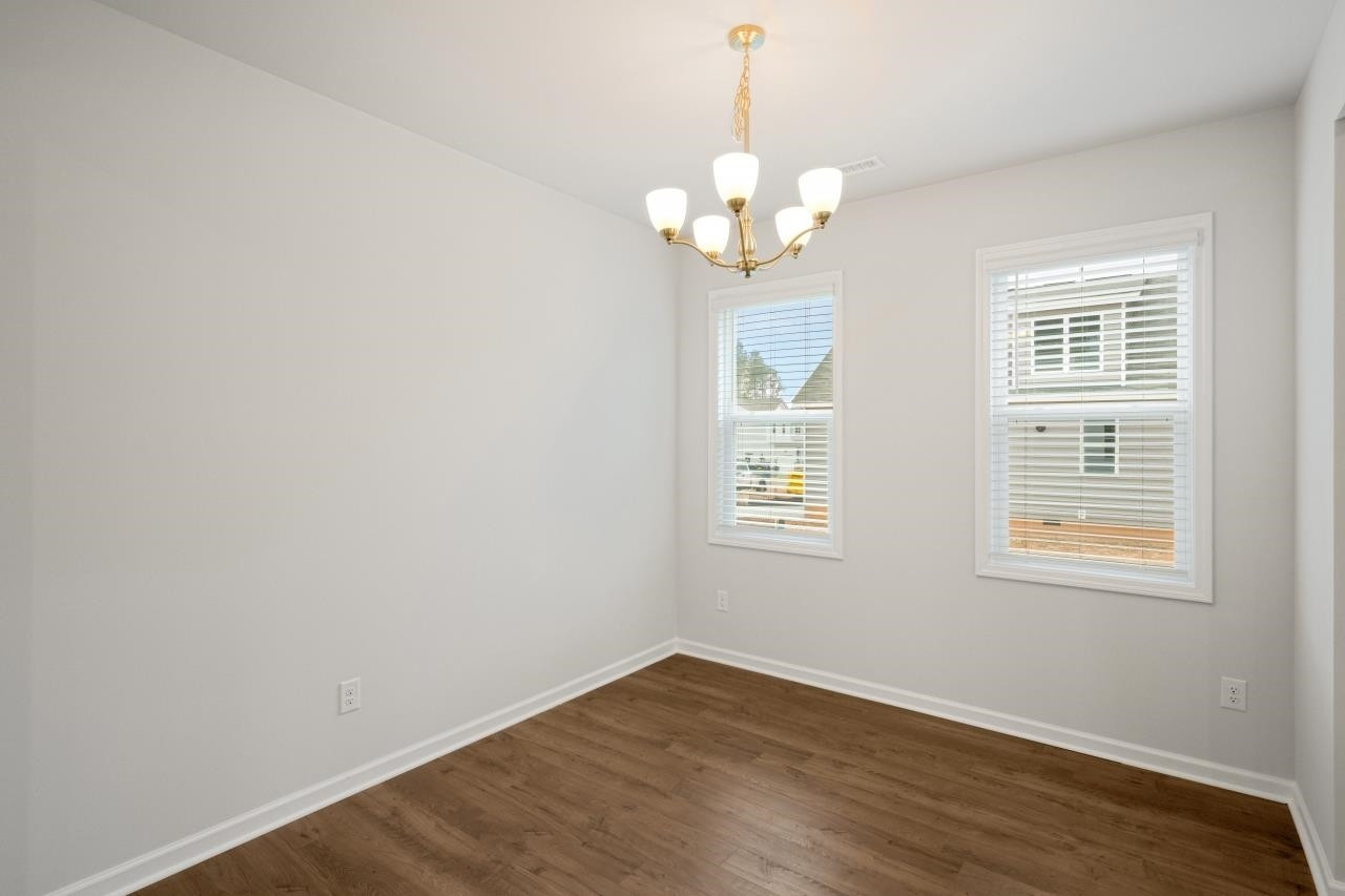 195 Madden Rose Loop Garner, NC 27529 - Photo 12 of 37 an empty room with wooden floor and windows