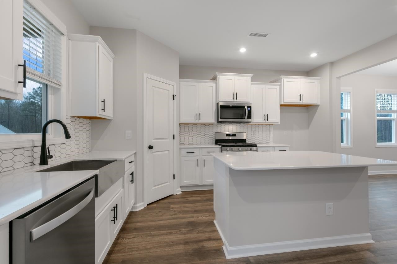 195 Madden Rose Loop Garner, NC 27529 - Photo 15 of 37 a kitchen with kitchen island a sink stainless steel appliances and cabinets