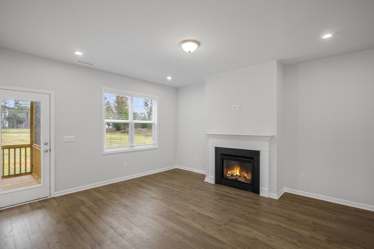 195 Madden Rose Loop Garner, NC 27529 - Photo 19 of 37 a view of an empty room with wooden floor fireplace and a window