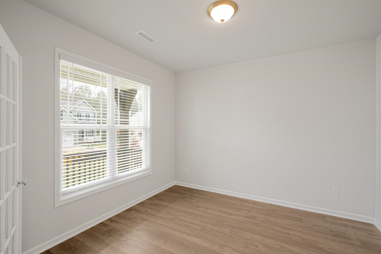 195 Madden Rose Loop Garner, NC 27529 - Photo 9 of 37 an empty room with wooden floor and windows
