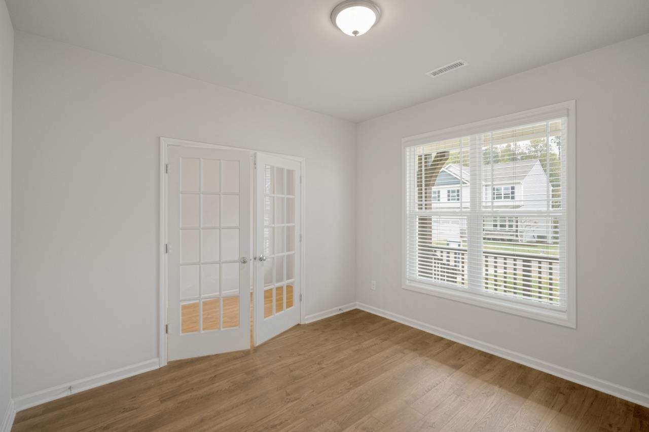 195 Madden Rose Loop Garner, NC 27529 - Photo 10 of 37 an empty room with wooden floor and windows