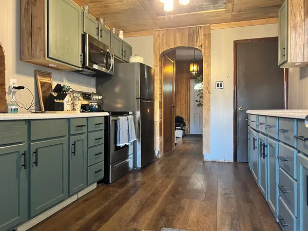 a kitchen with stainless steel appliances granite countertop a refrigerator a stove and a wooden floors