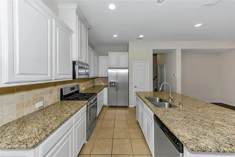 a large kitchen with granite countertop counter top space a sink stainless steel appliances and cabinets