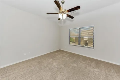 an empty room with ceiling fan and windows