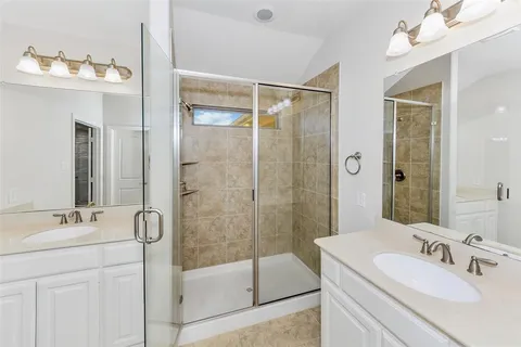 a bathroom with a double vanity sink mirror and shower