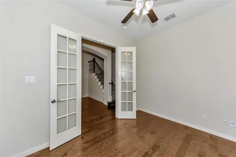 an empty room with wooden floor closet and windows