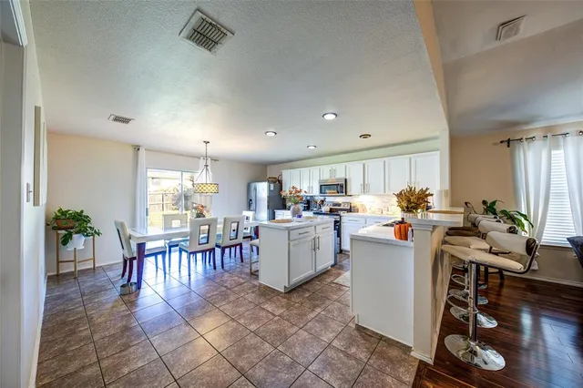 a kitchen with a dining table chairs and a view of living room