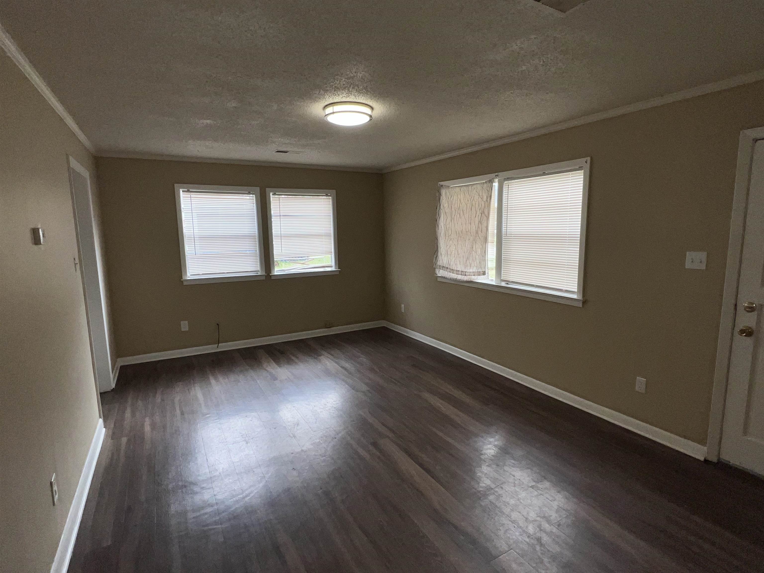 892 Restbrook Avenue Memphis, TN 38127 - Photo 3 of 11 Empty room featuring a textured ceiling, dark wood-style flooring, and ornamental molding