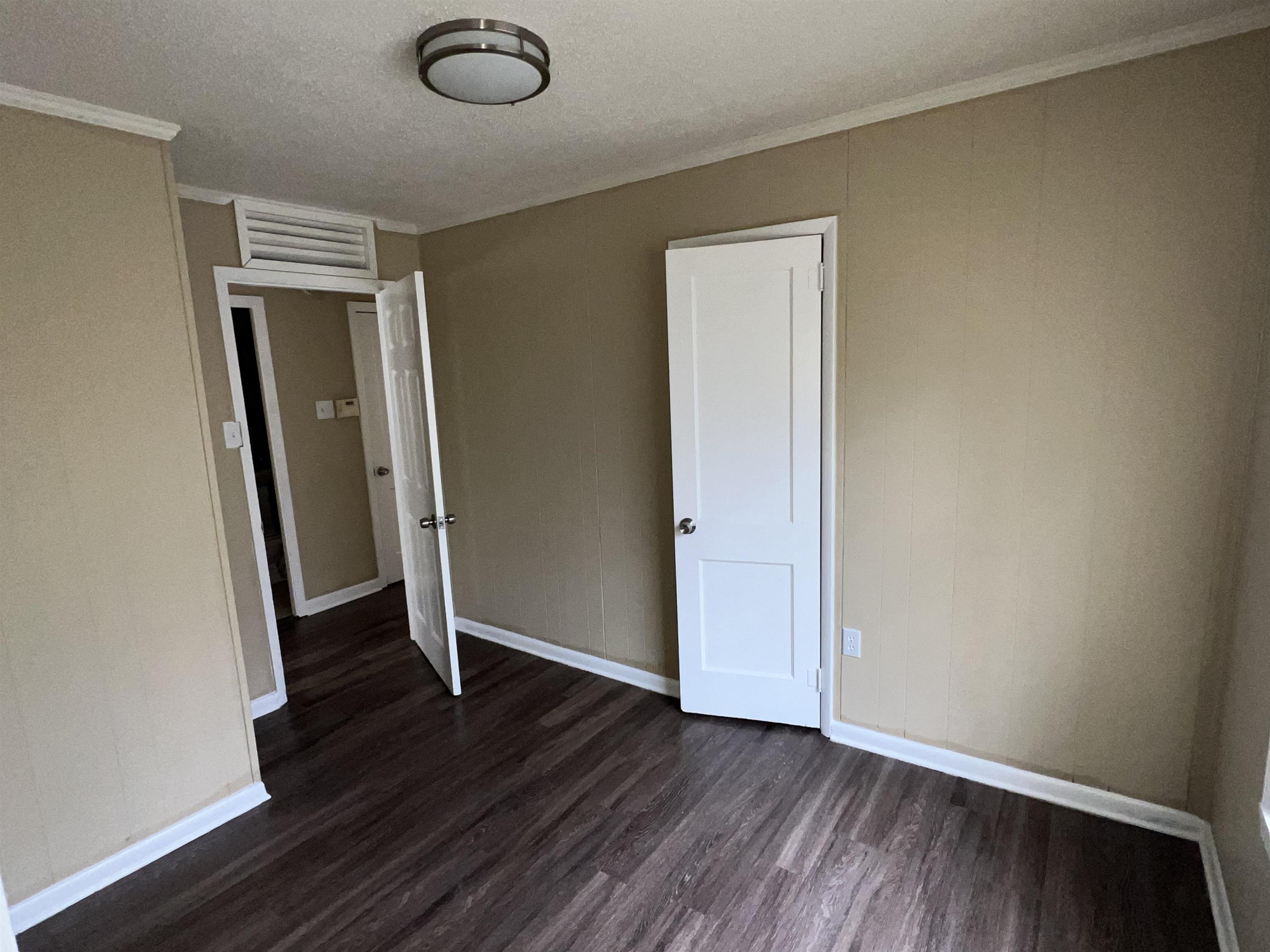 892 Restbrook Avenue Memphis, TN 38127 - Photo 7 of 11 Unfurnished bedroom featuring crown molding, dark wood-type flooring, and a textured ceiling