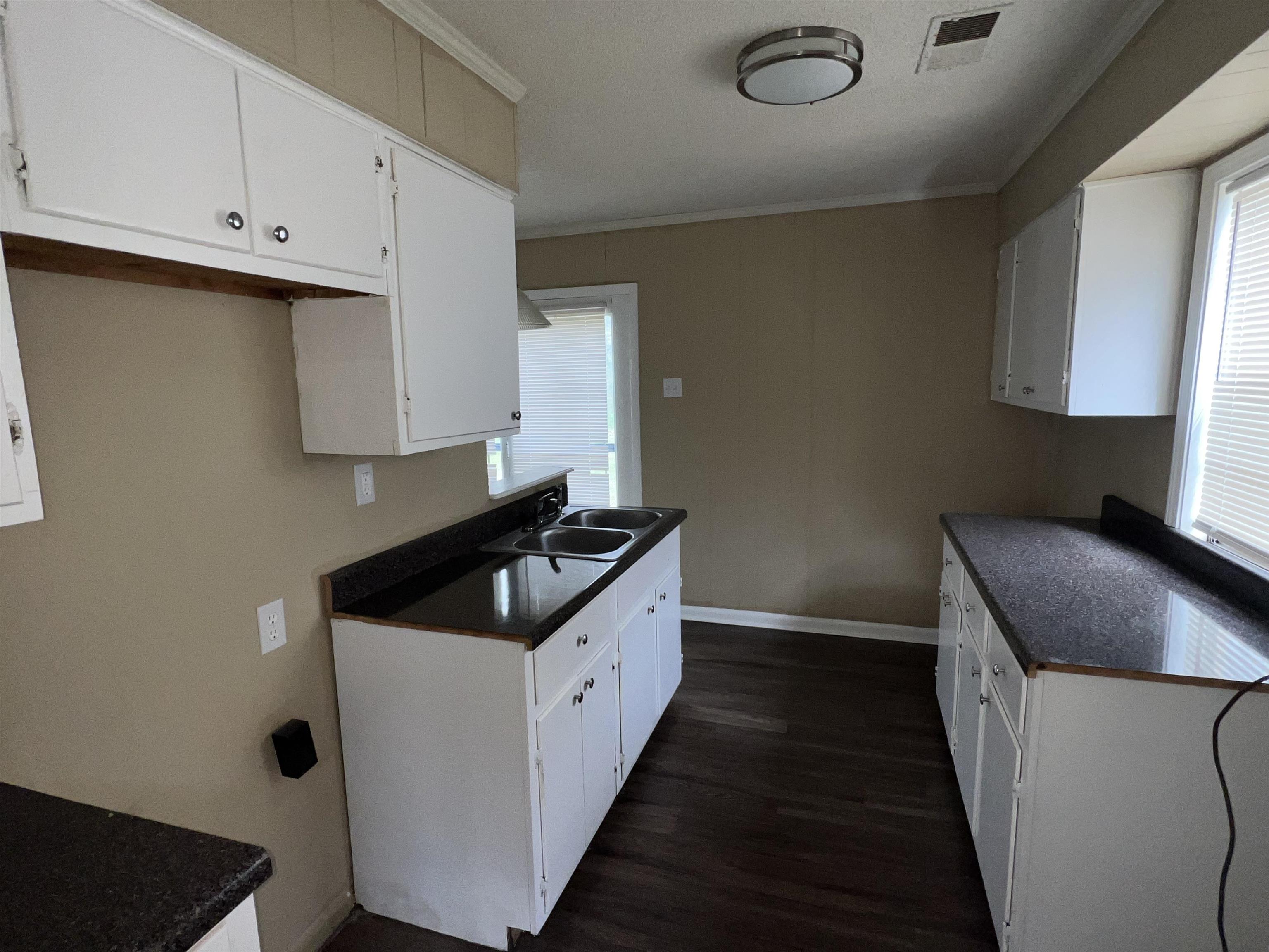 892 Restbrook Avenue Memphis, TN 38127 - Photo 8 of 11 Kitchen with white cabinets, ornamental molding, and dark wood-style floors