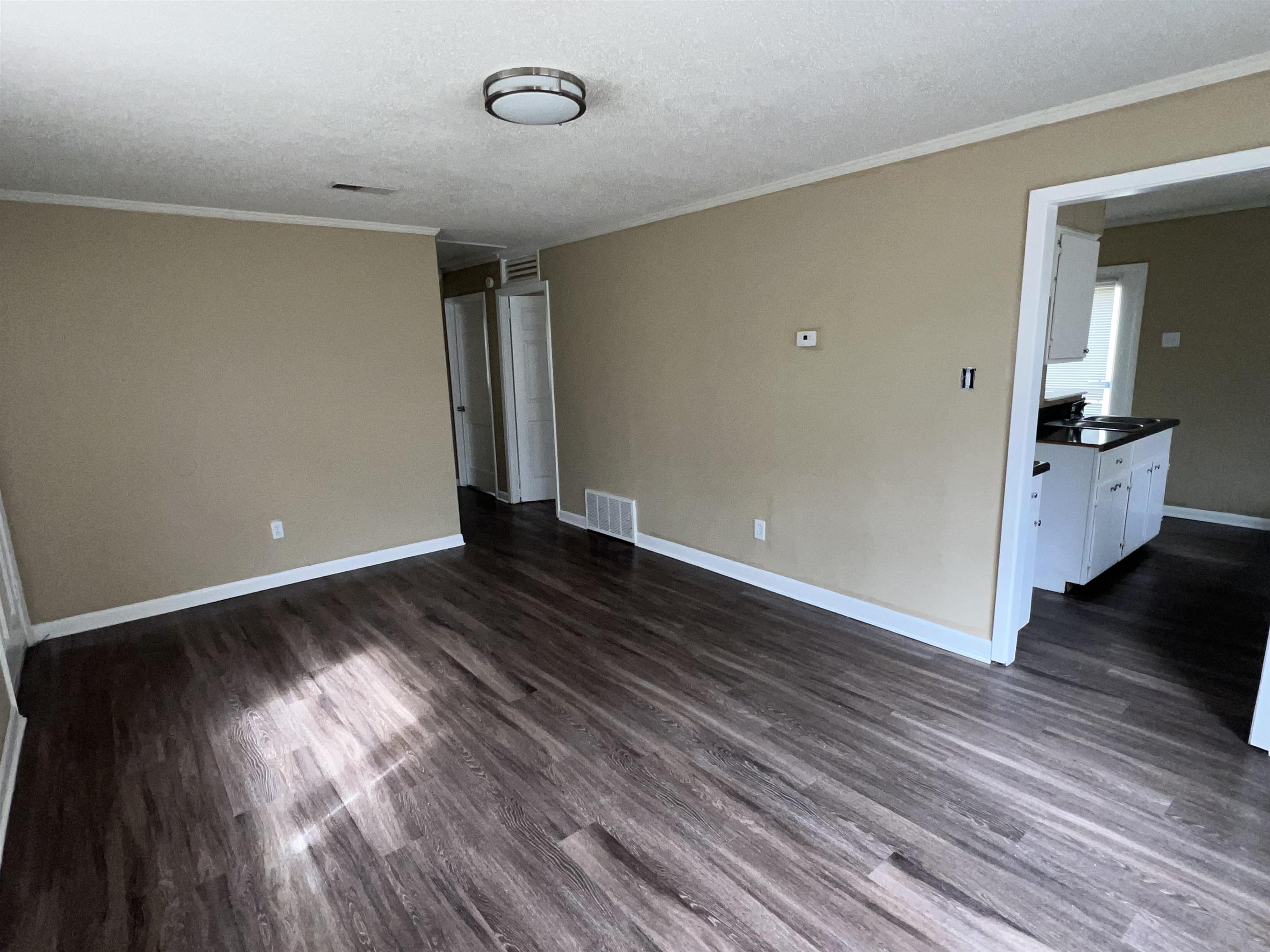 892 Restbrook Avenue Memphis, TN 38127 - Photo 9 of 11 Spare room featuring crown molding, dark wood-style flooring, and a textured ceiling