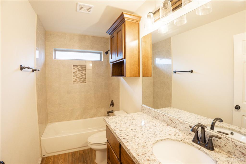 8725 Spoonbill Street Harlingen, TX 78552 - Photo 15 of 18 a bathroom with a granite countertop sink a toilet and shower