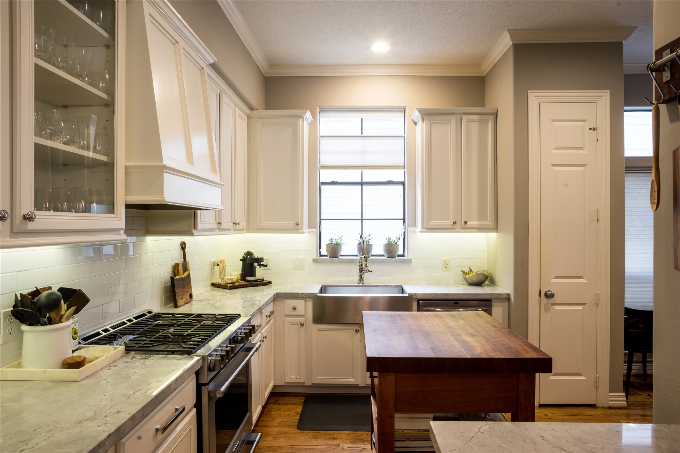 1611 McDonald Street Houston, TX 77007 - Photo 6 of 37 Updated kitchen offers a combination of display and white cabinetry, with a paneled vent hood demonstrating seamless design.