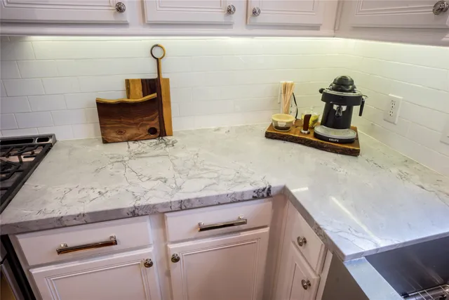 a kitchen with stainless steel appliances granite countertop a refrigerator stove and white cabinets