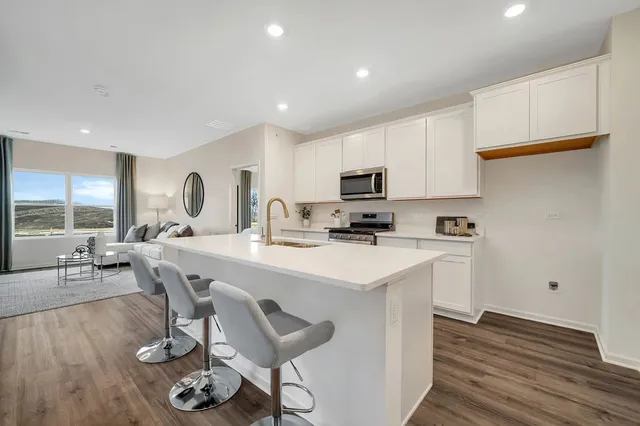 a kitchen with a sink a stove a refrigerator cabinets and dining table