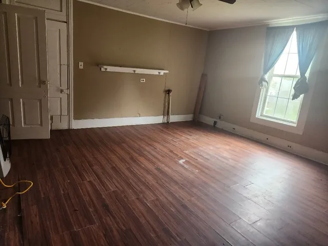 a view of a hallway with wooden floor and a bathroom
