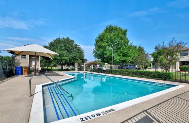 a view of a swimming pool with lawn chairs under an umbrella