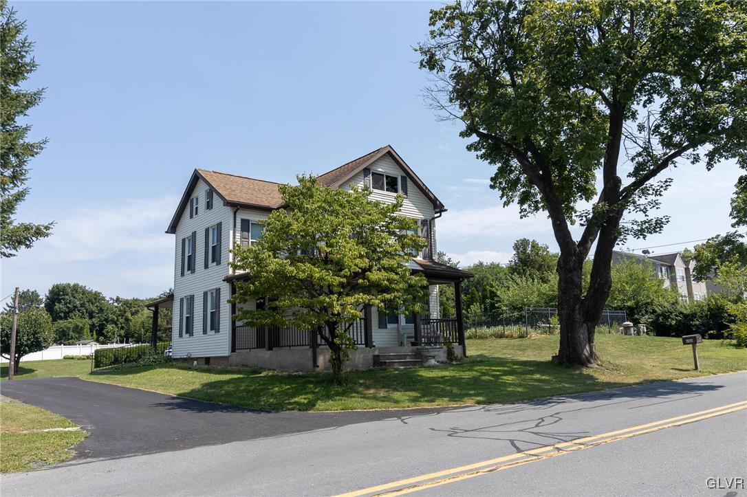 a view of a house with a yard and large trees