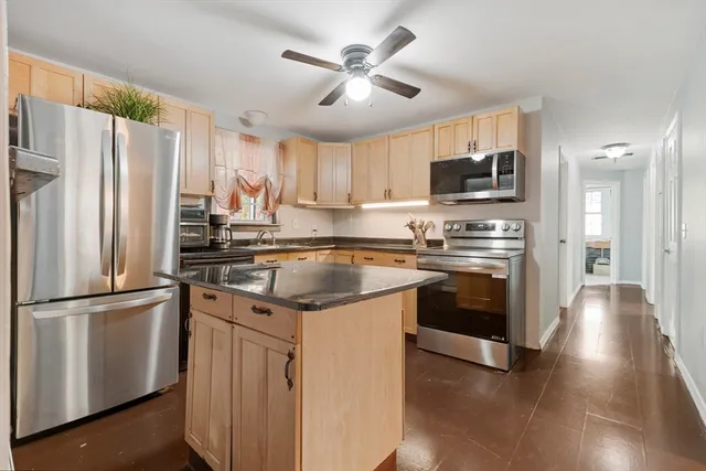 a kitchen with kitchen island granite countertop a sink appliances cabinets and a counter space