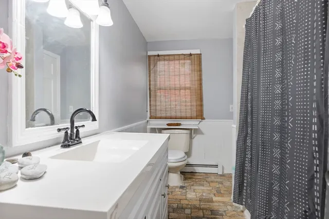 a bathroom with a granite countertop sink a toilet and shower
