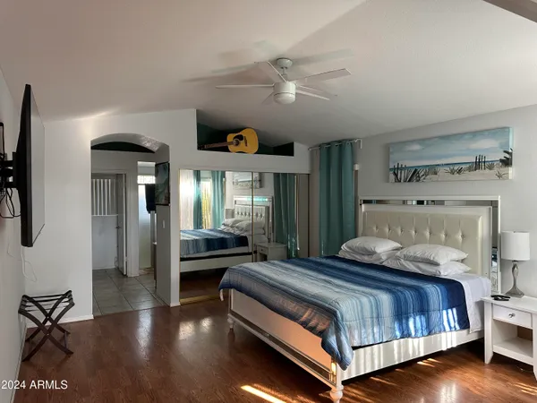 a bedroom with a bed and a large mirror with wooden floor