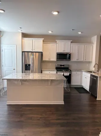 a living room with stainless steel appliances granite countertop a refrigerator a stove top oven a sink and dishwasher with wooden floor