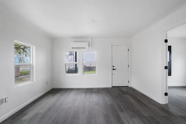 an empty room with wooden floor and windows