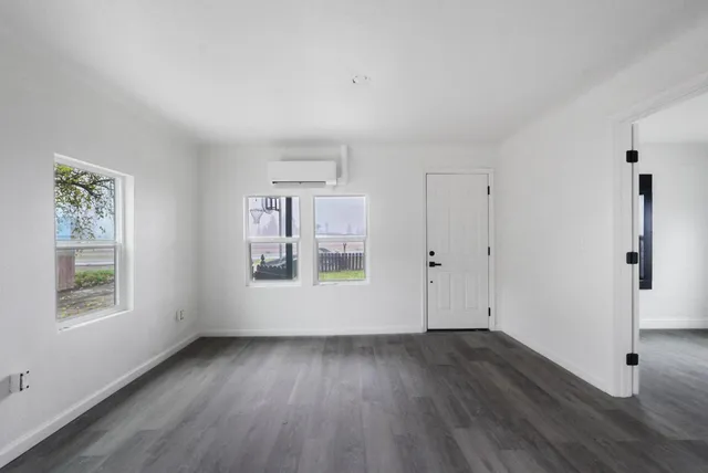 an empty room with wooden floor and windows
