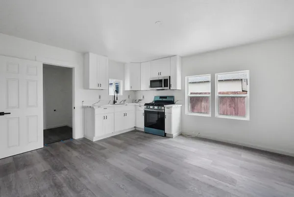 a kitchen with stainless steel appliances a sink wooden floor and cabinets