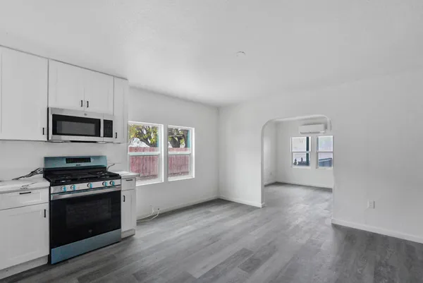 a kitchen with granite countertop a stove a sink and a microwave