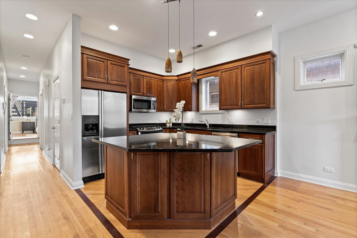 2642 North Racine Avenue, Unit 2N Chicago, IL 60614 - Photo 6 of 22 a kitchen with stainless steel appliances granite countertop a refrigerator a sink dishwasher a stove and a dining table with wooden floor