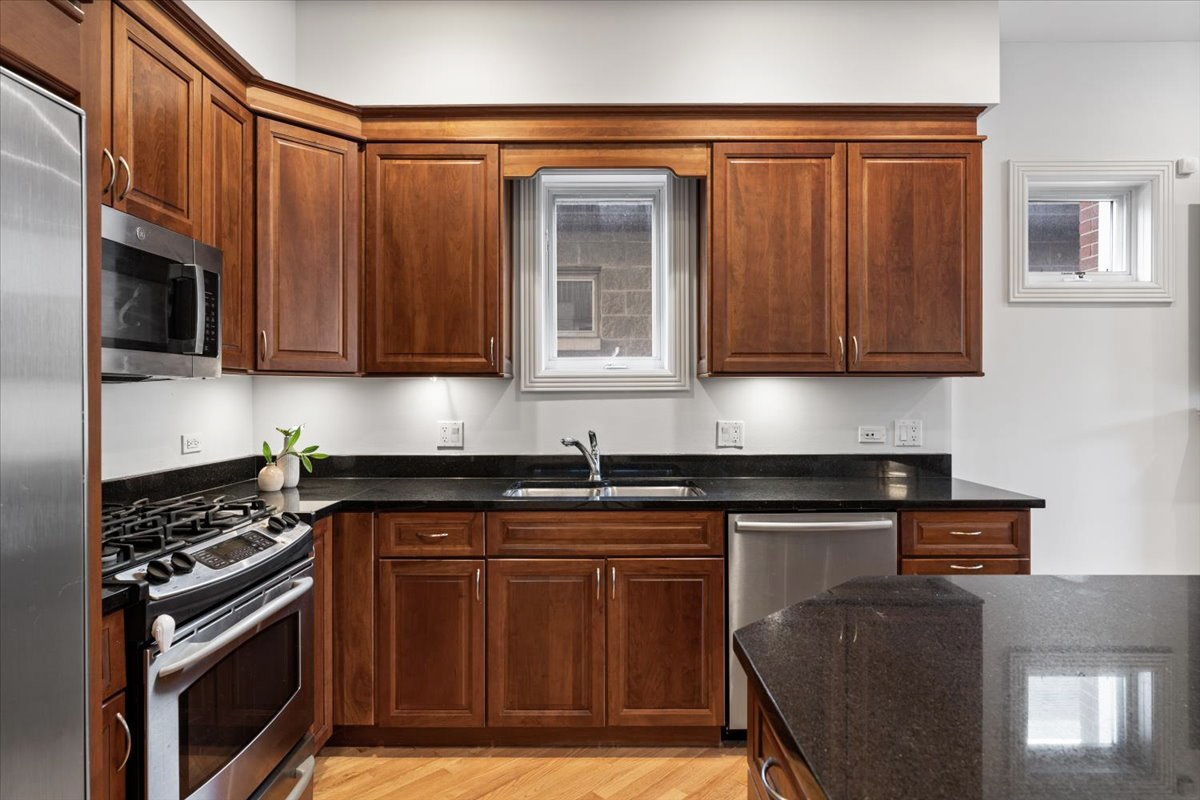 2642 North Racine Avenue, Unit 2N Chicago, IL 60614 - Photo 8 of 22 a kitchen with granite countertop wooden cabinets and a stove top oven