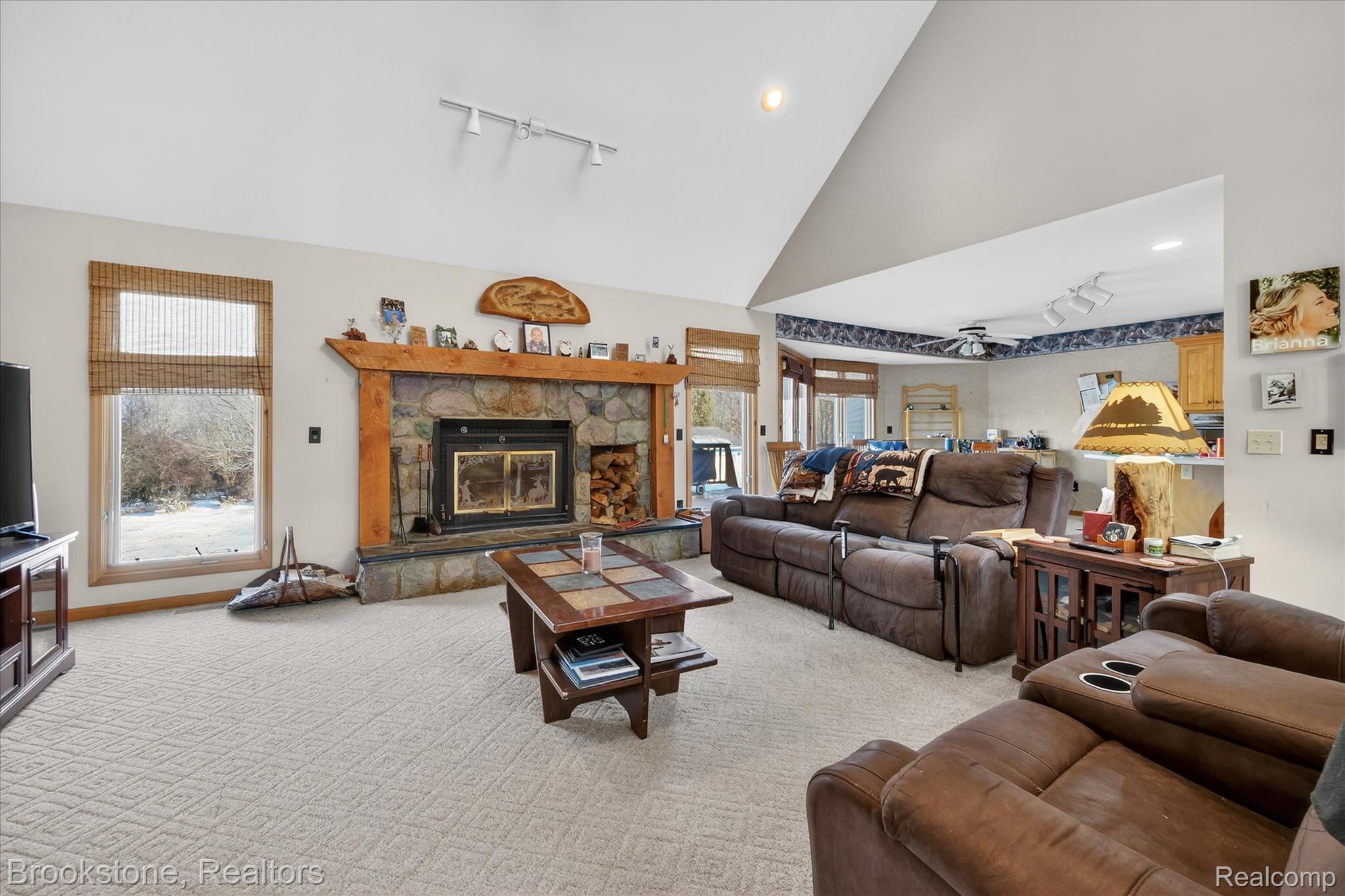 5163 Country Squire Road Dryden, MI 48428 - Photo 16 of 64 Living area with high vaulted ceiling, track lighting, carpet flooring, a stone fireplace, and plenty of natural light