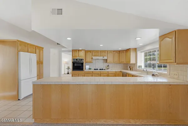 a large white kitchen with kitchen island a sink a large window and a counter top space