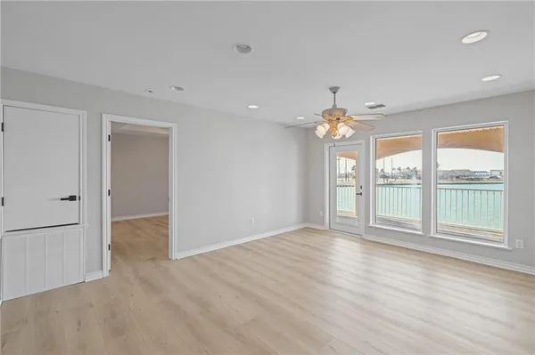 a view of an empty room with a window and wooden floor