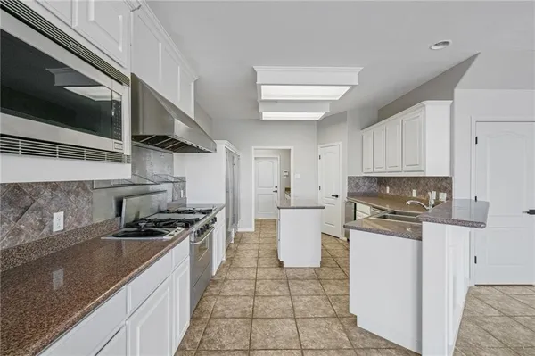 a kitchen with stainless steel appliances granite countertop a sink stove and cabinets