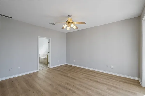 a view of an empty room with chandelier fan and wooden floor