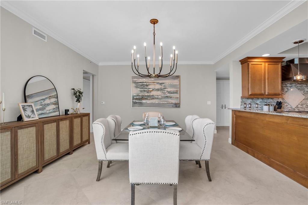 265 Indies Way, Unit 1402 Naples, FL 34110 - Photo 16 of 44 Dining room with ornamental molding, an inviting chandelier, and light tile flooring