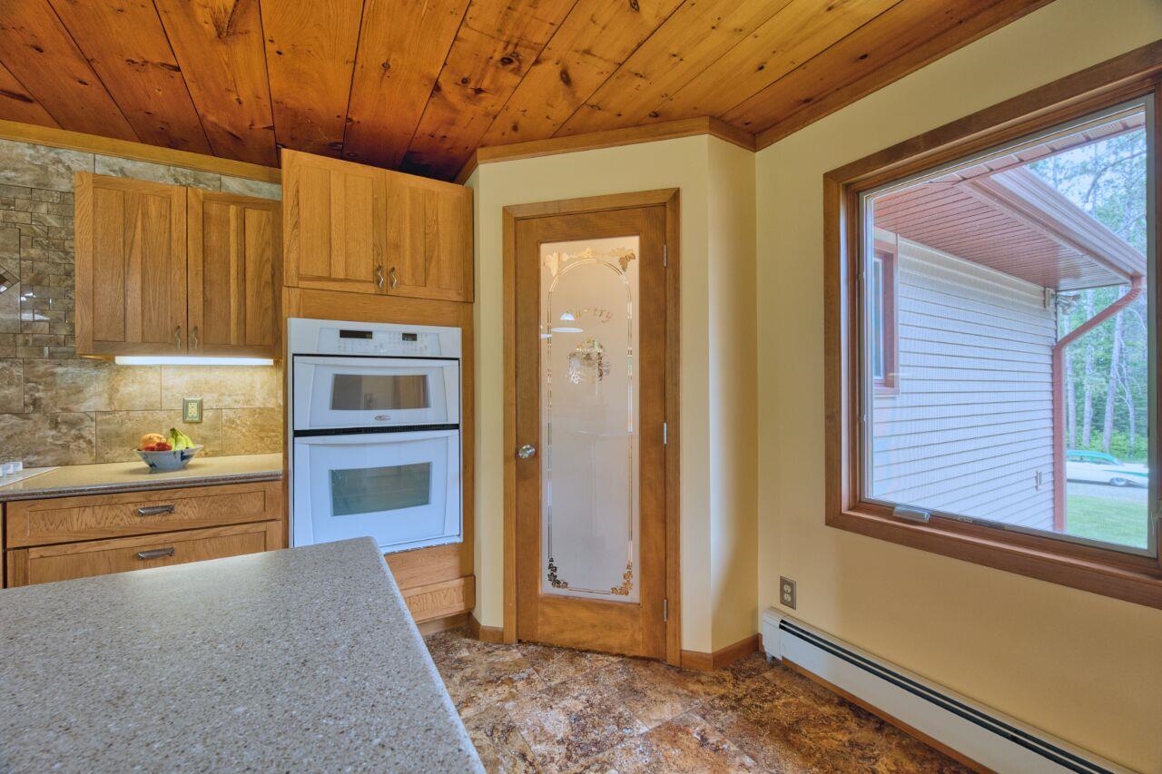 9220 Biss Road Britt, MN 55710 - Photo 9 of 50 Kitchen with a baseboard heating unit, double oven, wooden ceiling, baseboards, and decorative backsplash