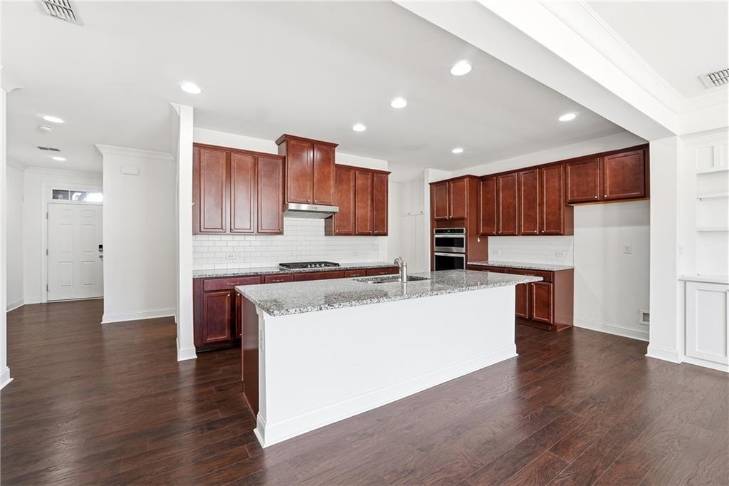 3425 Hardy Street Cumming, GA 30041 - Photo 11 of 25 a large kitchen with stainless steel appliances kitchen island a stove a refrigerator a oven and a wooden cabinets