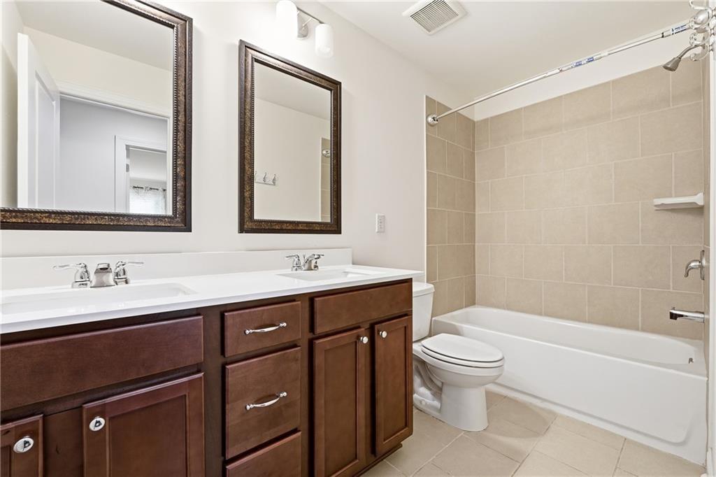 3425 Hardy Street Cumming, GA 30041 - Photo 22 of 25 a bathroom with a toilet a sink a mirror a shower a vanity and window