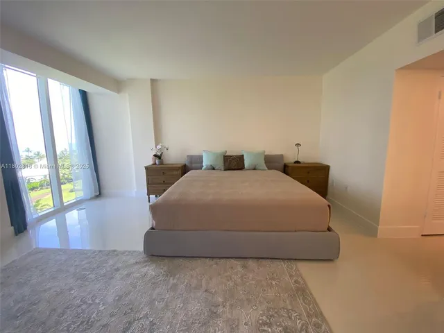 a spacious bedroom with a bed and a large window