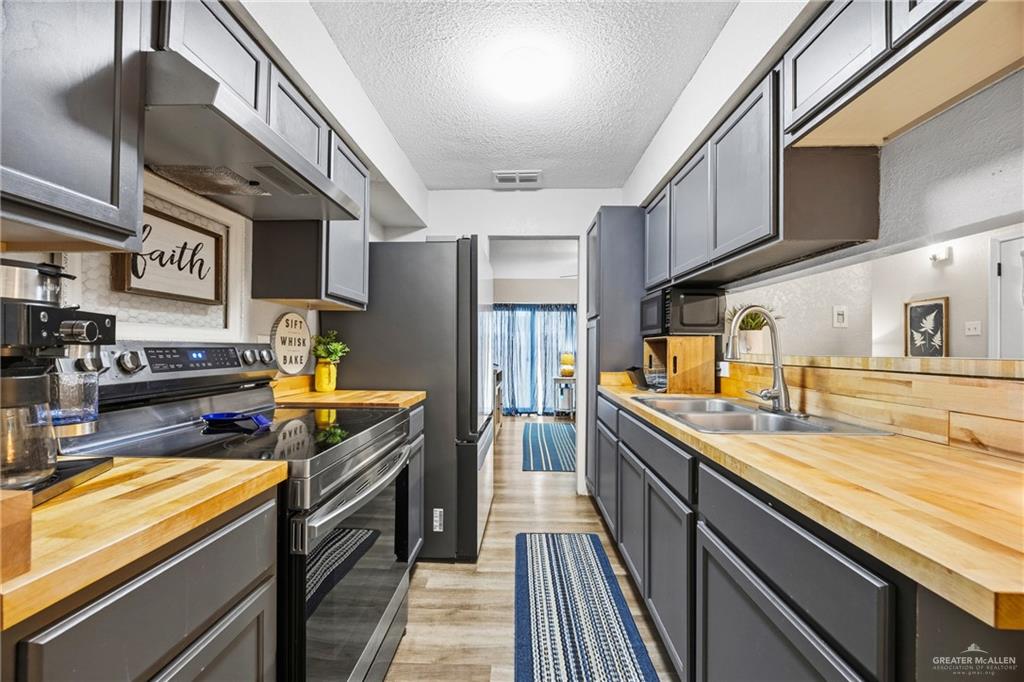 2004 Hawk Avenue McAllen, TX 78504 - Photo 5 of 15 a kitchen with stainless steel appliances granite countertop a sink a stove and cabinets