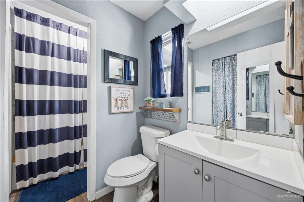 2004 Hawk Avenue McAllen, TX 78504 - Photo 10 of 15 a bathroom with a sink a toilet a mirror and shower curtain