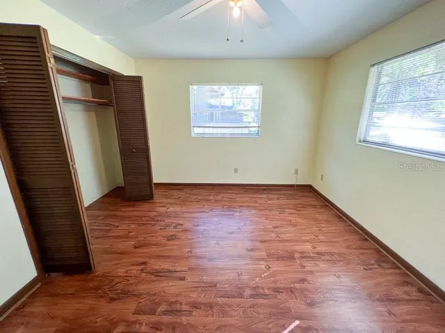an empty room with wooden floor and windows