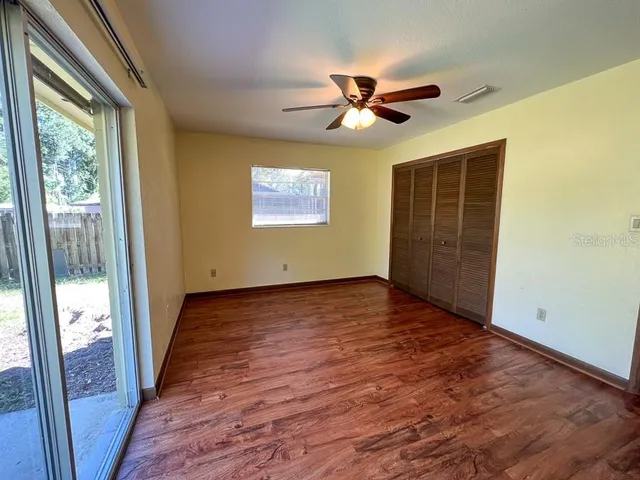 a view of empty room with wooden floor and fan